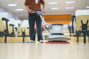 Moving with floor buffer to clean the floor