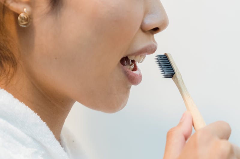 Person using eco-friendly bamboo toothbrush for sustainable daily oral care routine