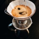 Person pouring water over a pour-over coffee filter for eco-friendly brewing